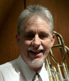 Len smiling holding a trombone